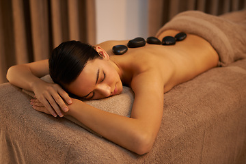 Image showing Bed, woman and massage with stone at spa for stress relief, organic body health and detox. Towel, relax and zen female person with hot rock for wellness, self care and spiritual healing at resort
