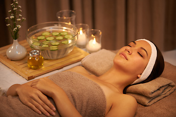 Image showing Sleeping, relax and woman at massage table in spa with cucumber for peace, calm or skincare. Body, salon and person resting for aromatherapy with candles for natural beauty or health with eyes closed