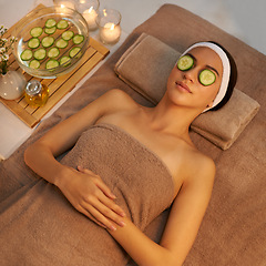 Image showing Top view, skincare and woman with cucumber on face at massage table in spa for peace, relax or wellness. Facial, above or person with vegetable on eyes for natural beauty or healthy organic treatment