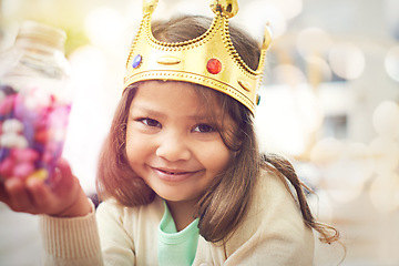 Image showing Candy, girl or princess with crown in portrait, home or castle with queen costume, sweets or royal tiara. Play, happiness or face of a child or kid with smile, development or fantasy game in a house