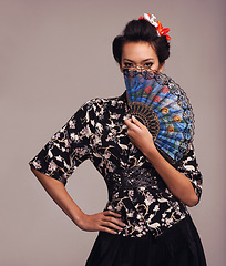 Image showing Asian woman, fashion and hand fan with confidence in studio on brown background in traditional style and elegant. Portrait, Japanese and female person with designer clothes or outfit for culture