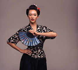 Image showing Asian woman, clothes and hand fan with confidence in studio on brown background in traditional style and elegant. Portrait, Japanese and female person with designer, fashion and outfit for heritage