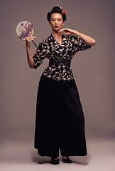 Image showing Fashion, fan and Japanese woman with geisha and Asian clothing with traditional outfit in studio. Culture, creative and ancient heritage clothes with female person from Japan with brown background