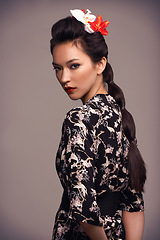 Image showing Fashion, portrait and Japanese woman with geisha, flower and Asian clothing with traditional outfit in studio. Culture, creative and heritage clothes with person from Japan with brown background