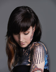 Image showing Creativity, ink and woman with tattoo in studio for creative design, trendy and body art with color. Female person, funky and edgy with artistic, blue and red for bold statement in gray background