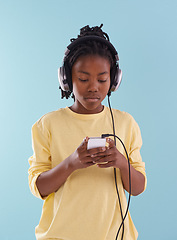 Image showing Phone, music and black boy with headphones in studio for internet, playlist or search on blue background. Smartphone, radio and teen model with app for podcast, streaming or sign up subscription