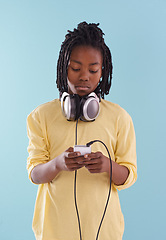 Image showing Music, headphones and black kid in studio for internet, playlist or track search on blue background. Smartphone, radio and African teen boy with app for podcast, streaming or sign up subscription