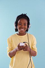 Image showing Music, phone and boy portrait with headphones in studio for internet, playlist or search on blue background. Smartphone, radio and teen model with app for podcast, streaming or sign up subscription