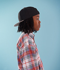 Image showing Fashion, children or black boy with cap in studio for confidence, style or streetwear aesthetic on blue background. Face, profile or African teen male model with cool, clothes or trendy outfit choice