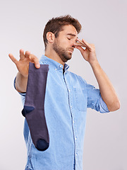 Image showing Man, smelly socks and closing nose for poor hygiene with clothes, bad odor or stink with disgust isolated on white background. Unpleasant, dirty and foul with negative reaction for stench in studio