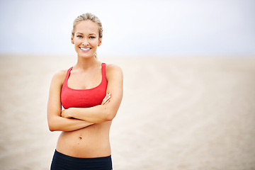 Image showing Woman, portrait and fitness on beach sand with arms crossed, confident and smile with wellness and outdoor. Exercise, athlete and sports with happiness for health, marathon or race for cardio workout