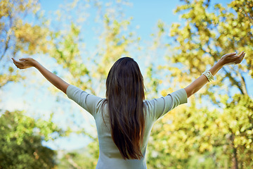 Image showing Person, back and freedom in nature for outdoor wellness, travel and fresh air in environment and spring. Behind with casual and carefree hands by trees with celebration and stretching arms in a park