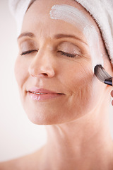 Image showing Mature woman, face mask and brush in studio for skincare or anti aging on self care, wellness and fresh skin. Closeup, female person and glow with smile or happy for facial and beauty or luxury