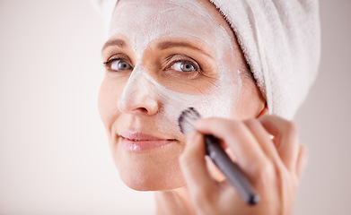 Image showing Face, mature woman and mask with brush in studio for skincare or anti aging on self care, wellness and fresh skin. Closeup, female person and glow with smile or happy for facial and beauty for luxury