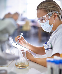 Image showing Woman, scientist and writing with mask for research, checklist or test results from experiment at laboratory. Female person or medical professional takings notes in exam or trial on chemical compound