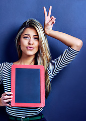 Image showing Portrait, blackboard and woman with peace, hands or mockup in studio for news or announcement on blue background. Frame, space and face of female model with v emoji for opinion, menu or promotion