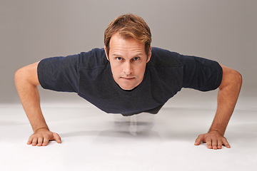 Image showing Man, portrait and push up with fitness or exercise in studio with workout, serious or training with confidence. Athlete, person and physical activity on gym floor for healthy body on white background