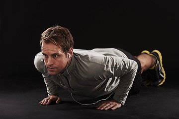 Image showing Man, face and push up with fitness or music in studio with exercise, workout and training with earphones. Athlete, person and bodybuilder on floor with audio, radio and podcast on black background