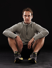 Image showing Break, portrait or runner in studio for fitness, running workout or exercise for health wellness. Tired, athlete and sports man sitting in training to relax for fatigue isolated on black background