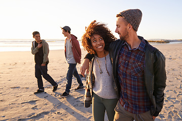 Image showing Beach, travel or couple of friends walking in nature for vacation, bonding or holiday together at sunset. Happy, journey or gen z group of people at sea for fresh air, conversation or ocean adventure