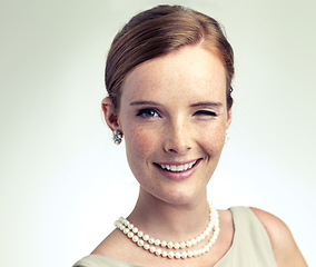 Image showing Portrait, fashion and happy woman wink in studio isolated on white background mockup space. Face, freckles or smile of young female person in vintage clothes for style with pearl necklace in Ireland