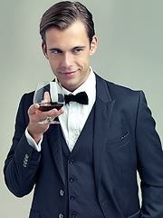 Image showing Glass, whiskey and young gentleman for idea in studio, happy and vintage fashion by white background. Alcohol, drinking and man in retro suit or tuxedo, bow tie and relax in smile at formal event