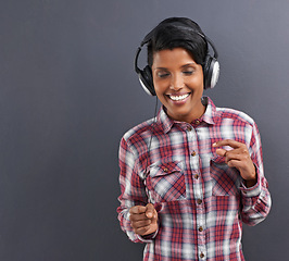 Image showing Happy woman, dancing and listening with headphones for music or podcast on a gray studio background. Young female person or Indian with smile, enjoying audio sound track with headset on mockup space