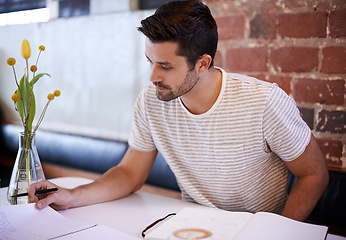 Image showing Young man, paperwork and coffee shop with documents for planning, reading or finance at indoor restaurant. Male person or freelancer checking financial budget, journal or planner in notebook at cafe