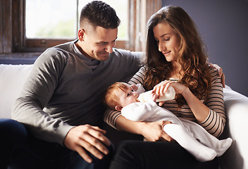 Image showing Mother, baby and milk feeding with dad in a family home with love, support and care together. Smile, relax and bottle for youth development and growth with mom and father on a living room sofa