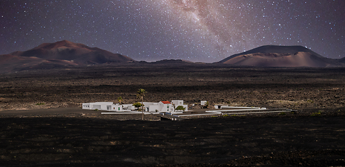 Image showing Amazing nocturnal panoramic landscape of volcano craters in Timanfaya national park. Milky way stars on night sky over La Gueria, Lanzarote island, Canary islans, Spain