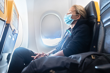 Image showing A young woman wearing face mask is traveling on airplane , New normal travel after covid-19 pandemic concept.