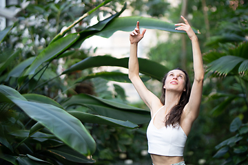 Image showing Female meditating and practicing yoga in tropical rainforest. Beautiful young woman practicing yoga outdoor with tropical forest in background.