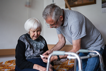 Image showing Man is helping an elderly woman with everyday tasks, helping with technology, setting video face time with her family using smart phone.