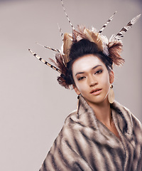 Image showing Woman, portrait and cultural fashion with Native American in tradition or art on a gray studio background. Female person with feather, face paint or stylish tribal clothing of goddess in beauty