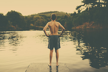 Image showing Teenager, lake and swimming for summer holiday at water for river vacation or camping, nature or back. Male person, relax and Australis traveling or explore forest at pier for weekend, break or rest