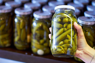 Image showing Woman, hand and jar of pickles in store for product selection or choice, shelf and shopping for condiments. Person, gherkins and glass with vegetable in vinegar, organic and nutrition for health.