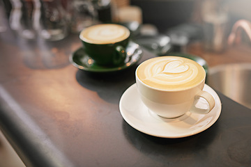 Image showing Coffee on counter, cup and latte with art for creativity, cappuccino or caffeine drink with pattern. Warm beverage on table, foam and milk with heart or leaf design, hospitality and service at cafe