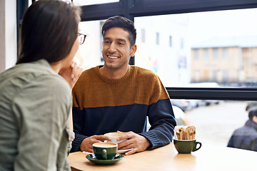 Image showing Couple, date and coffee shop with happy conversation and talking together with hot drink in a cafe. Man, smile and speaking about relationship in a restaurant with tea or cappuccino at a table