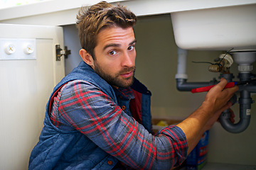 Image showing Man, portrait and plumbing with wrench for pipe repair, service or fix in home maintenance or indoor leak. Male person, plumber or handyman smile with water damage or sink with professional at house