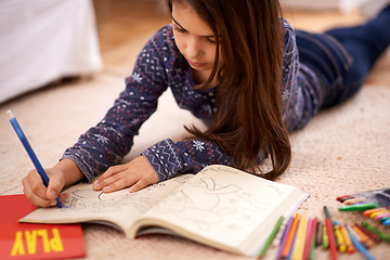 Image showing Girl, child and coloring book on floor for drawing in home with learning, development or art in lounge. Kid, pencil and education for studying, creativity or relax on carpet at family house in Madrid