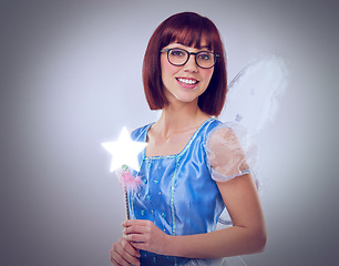 Image showing Studio, portrait and woman as fairy for magic, happiness and looking at wand for fantasy in background. Adult, female person and girl with butterfly wings, dress and model with joy and mystical