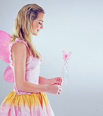 Image showing Studio, fairy and woman with smile for magic, happiness and looking at wand for fantasy in background. Adult, female person and girl with butterfly wings, dress and model with joy and mystical