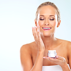 Image showing Woman, smile or face cream for skincare or wellness with cosmetics, aesthetic mockup or glow in studio. Dermatology, happy or confident model with space, shine or beauty lotion on blue background