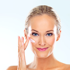 Image showing Woman, studio and portrait with cream on face for skincare, dermatology, and self care with smile. Female person, happy and facial product with lotion, cosmetics or beauty glow on blue background