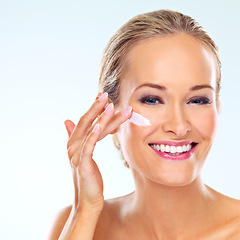 Image showing Happy, woman and portrait with cream on face for skincare, cosmetics, and self care in studio. Female person, smile and facial product with lotion, dermatology or beauty shine on blue background