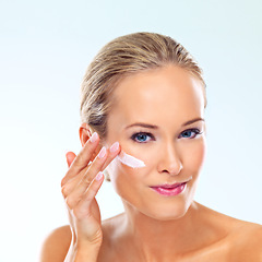 Image showing Woman, skincare and portrait with cream on face for cosmetics, dermatology, and self care in studio. Female person, confidence and product with lotion, moisturizer and application on blue background