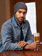 Image showing Portrait, beer and male person thinking at pub, drinks and restaurant for entertainment. Pensive, alcohol and bar for thoughtful or social for relax, smile and beanie for cold weather in England