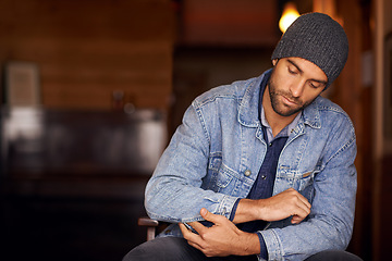 Image showing Man, trendy and winter fashion in home, house and hipster with serious male person sitting in warm clothes. Beanie, head wear for comfort, indoor and fixing denim jacket for urban trends in Canada