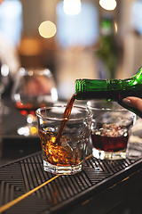 Image showing Close-up of a hand pouring amber whiskey