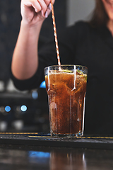 Image showing Close-up of a hand stirring a refreshing glass